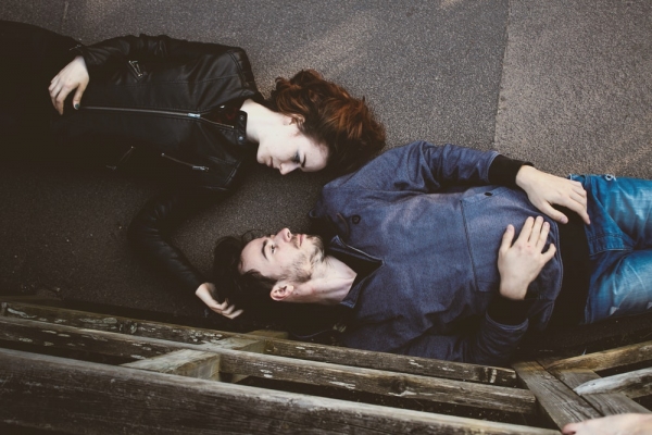 Overhead shot of man and woman laying on backs on walkway outdoors