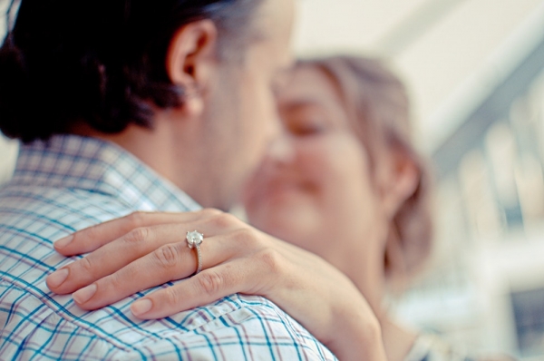 Bride's hand sits on groom's shoulder showing off her wedding ring