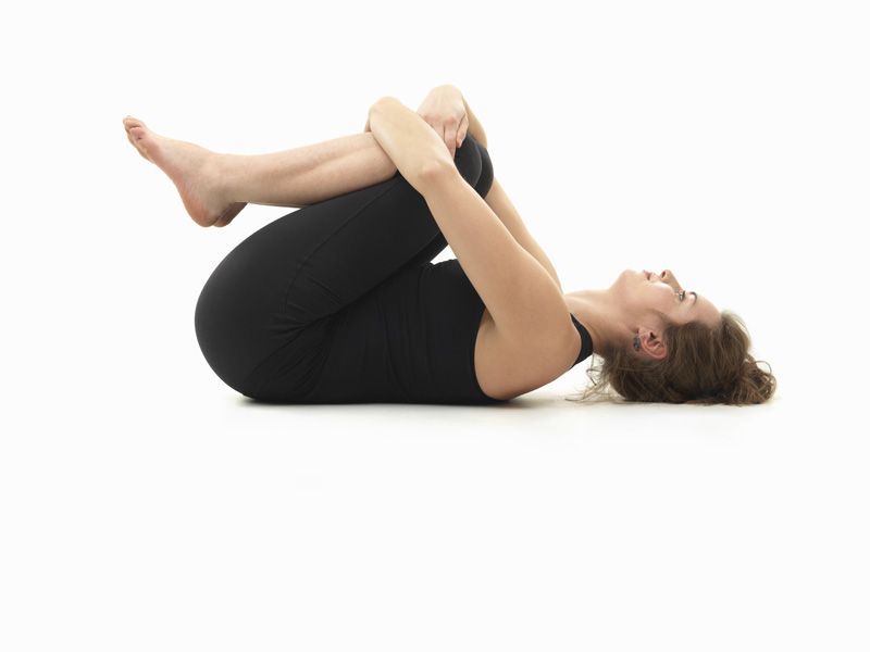 caucasian woman on the floor, in relaxed yoga pose, side view, dressed in black on white background