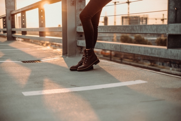 A woman on a rooftop wearing Timberland boots in front of a setting sun