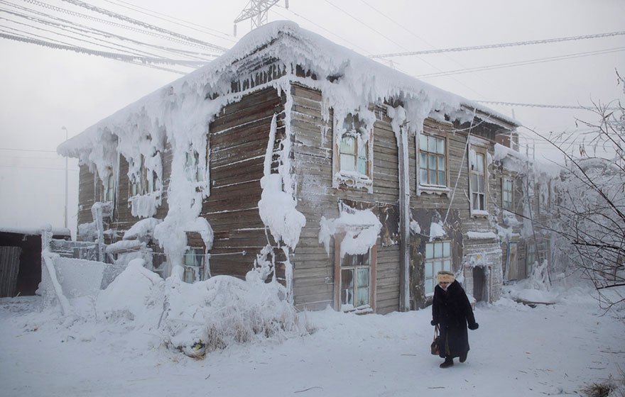 一名婦人走過村中一幢被冰雪覆蓋的小屋。<BR><BR>